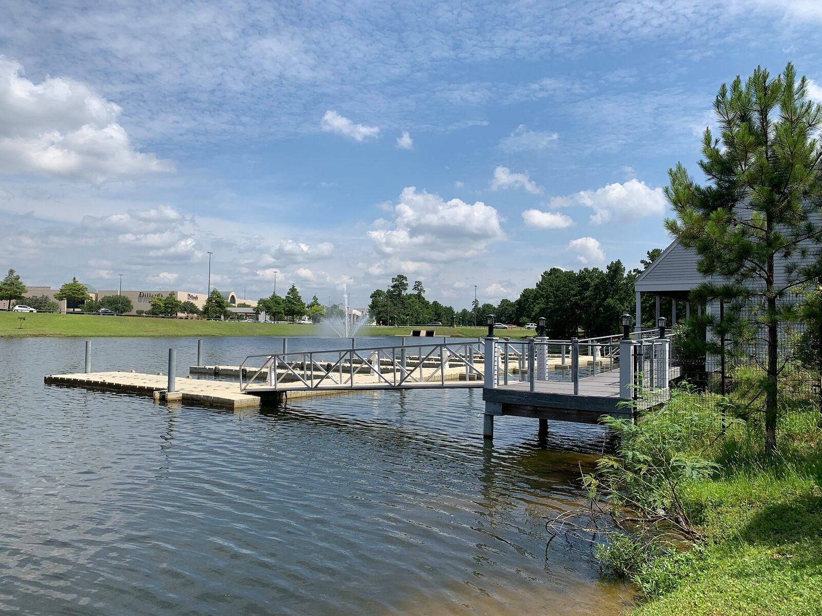 Large covered deck built out over a lake beside a gabled building, reached by an aluminum gangway from a floating dock section