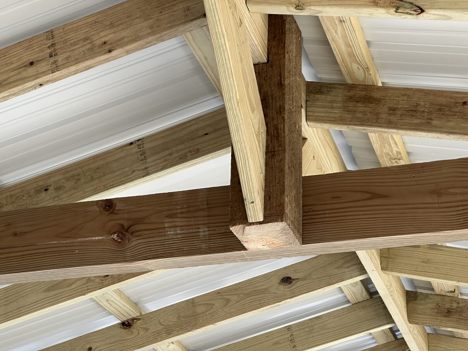Beam-over-post boathouse framing with rafters landing on the beam and metal roof deck above, dimensional treated timber throughout