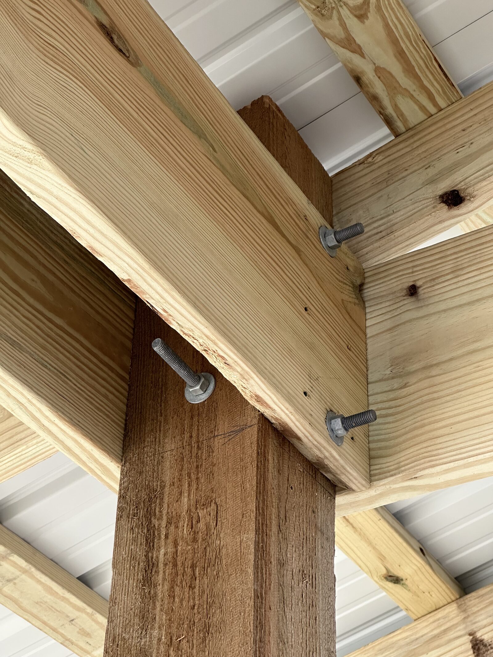 A timber post held between twin beams by three hot-dip galvanized machine bolts with washers, passing right through the assembly