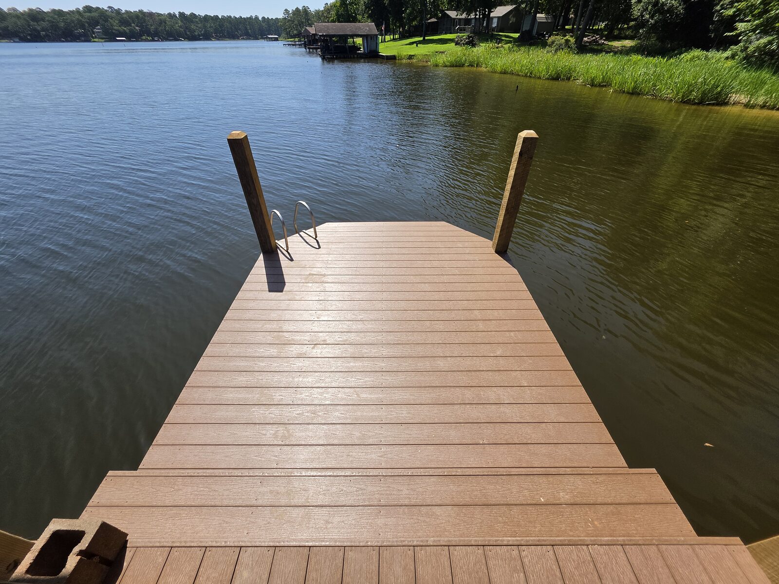 A composite-decked walkway running out over the water to a covered structure, timber posts and handrail either side