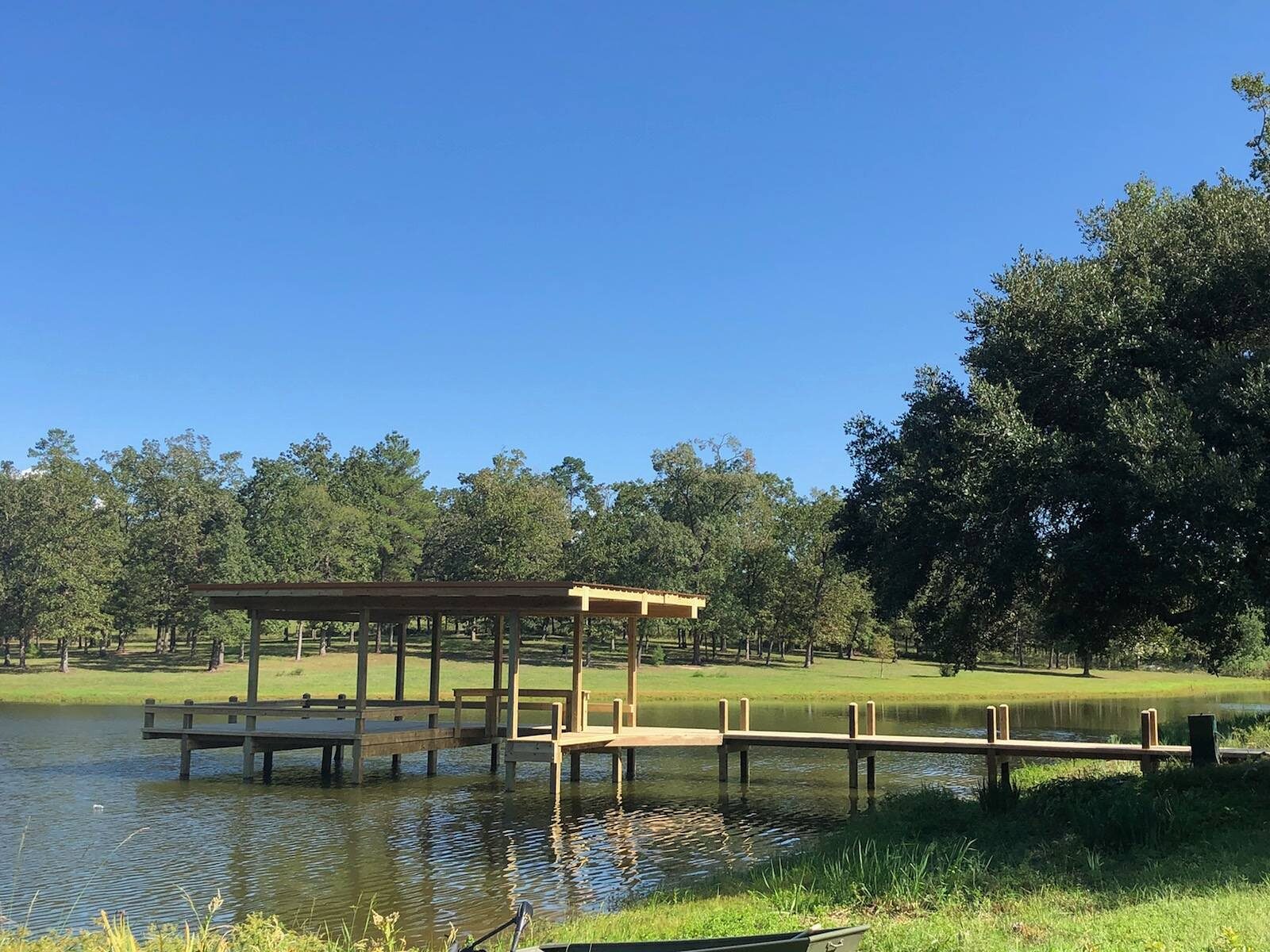 Covered timber pier head with a roof over the seating area and an open plank walkway running back to the bank