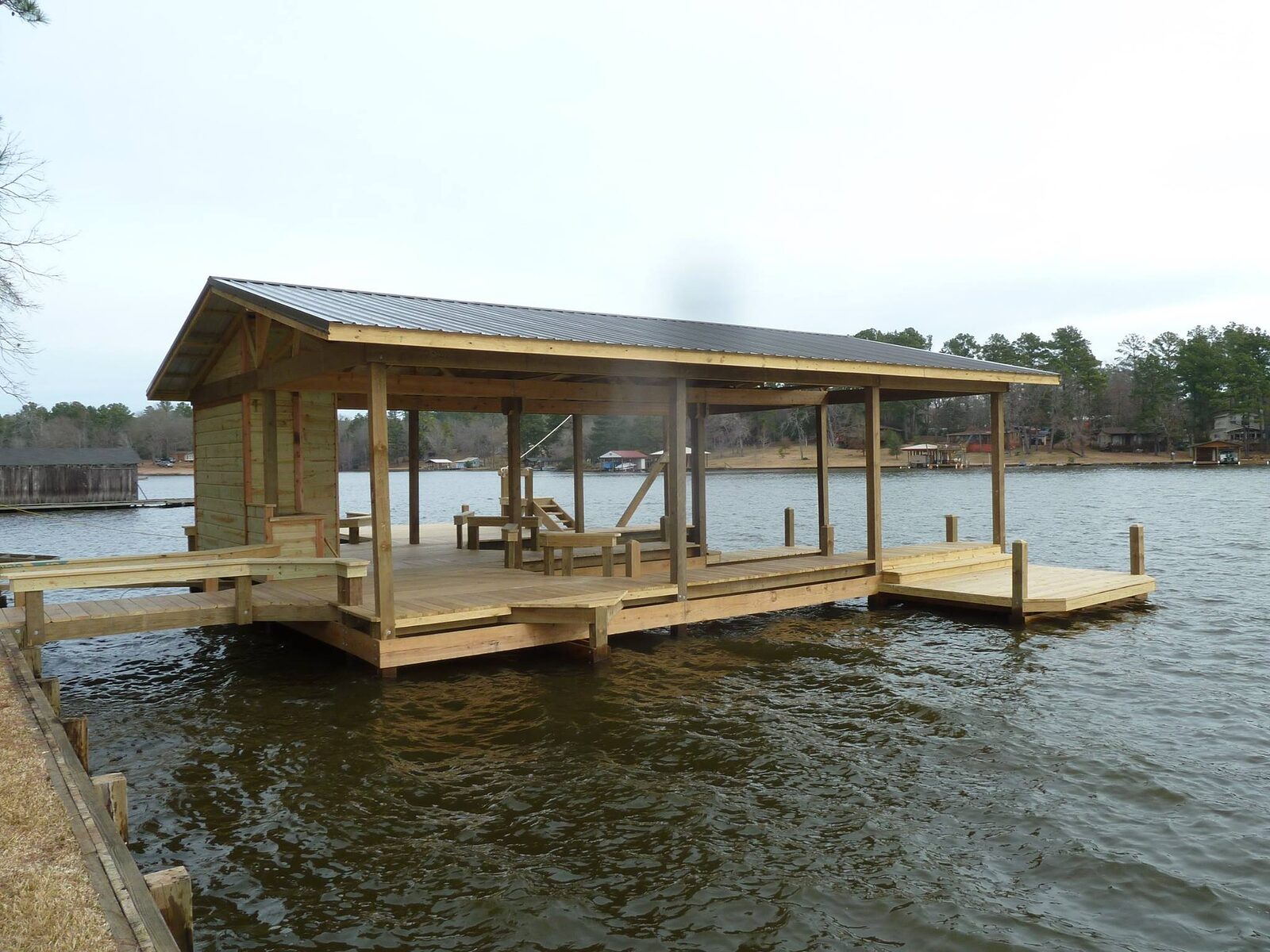 Finished boathouse with metal roof, enclosed storage room and wraparound dock over water