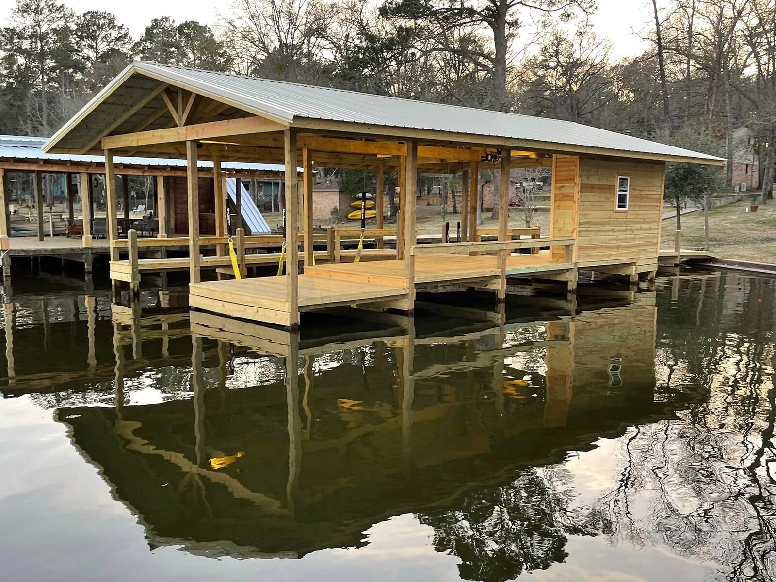 Gable-roof boathouse with covered slip and storage room built by Shoretech, reflected in still Houston County Lake water
