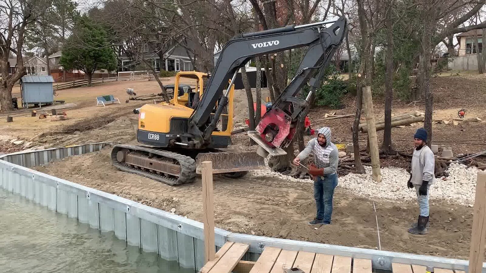 Excavator backfilling behind a newly driven galvanized steel sheet-pile bulkhead
