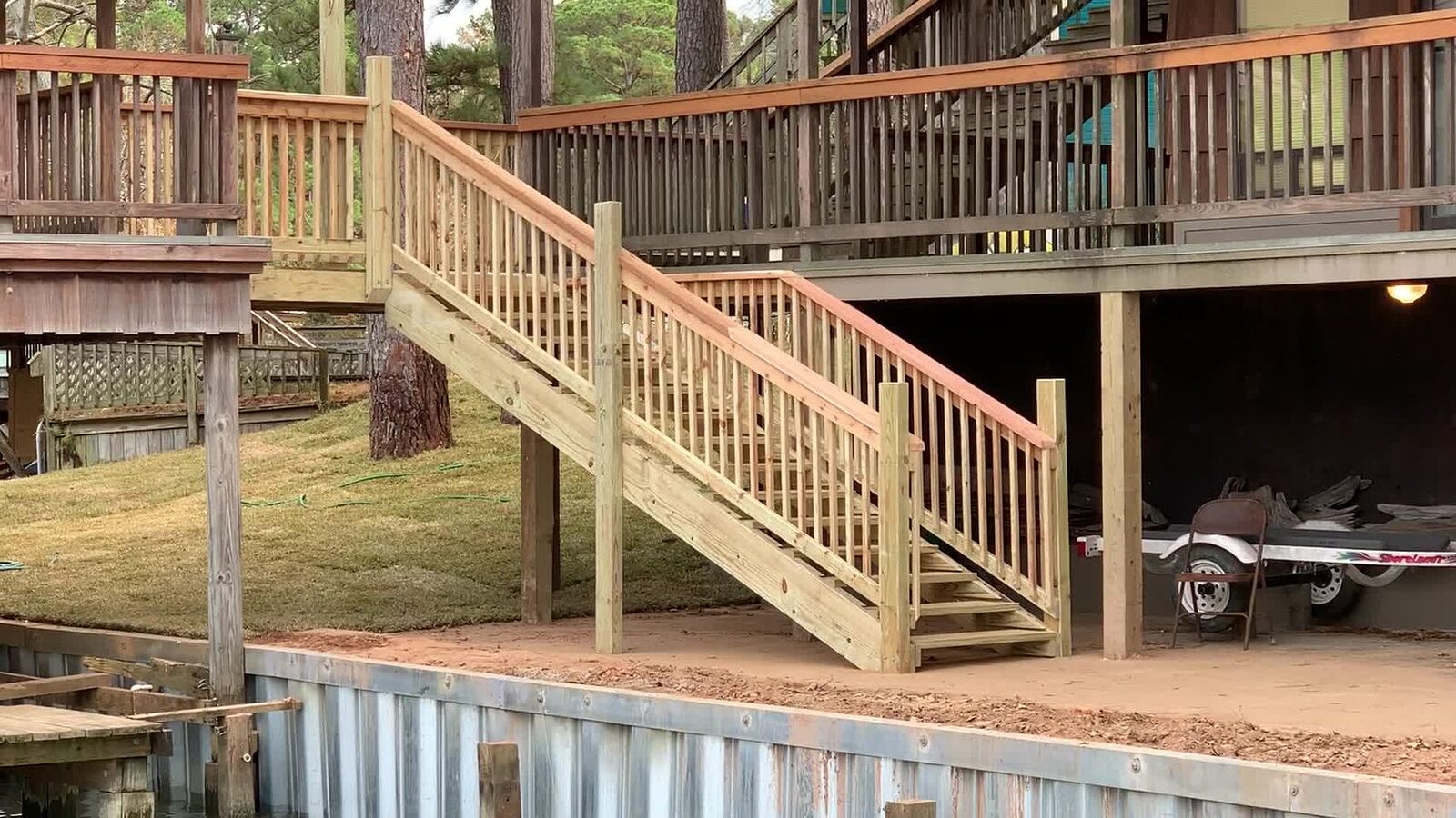 New timber stairway with matching rail running down from an elevated deck to grade, passing a galvanized steel bulkhead at the waterline
