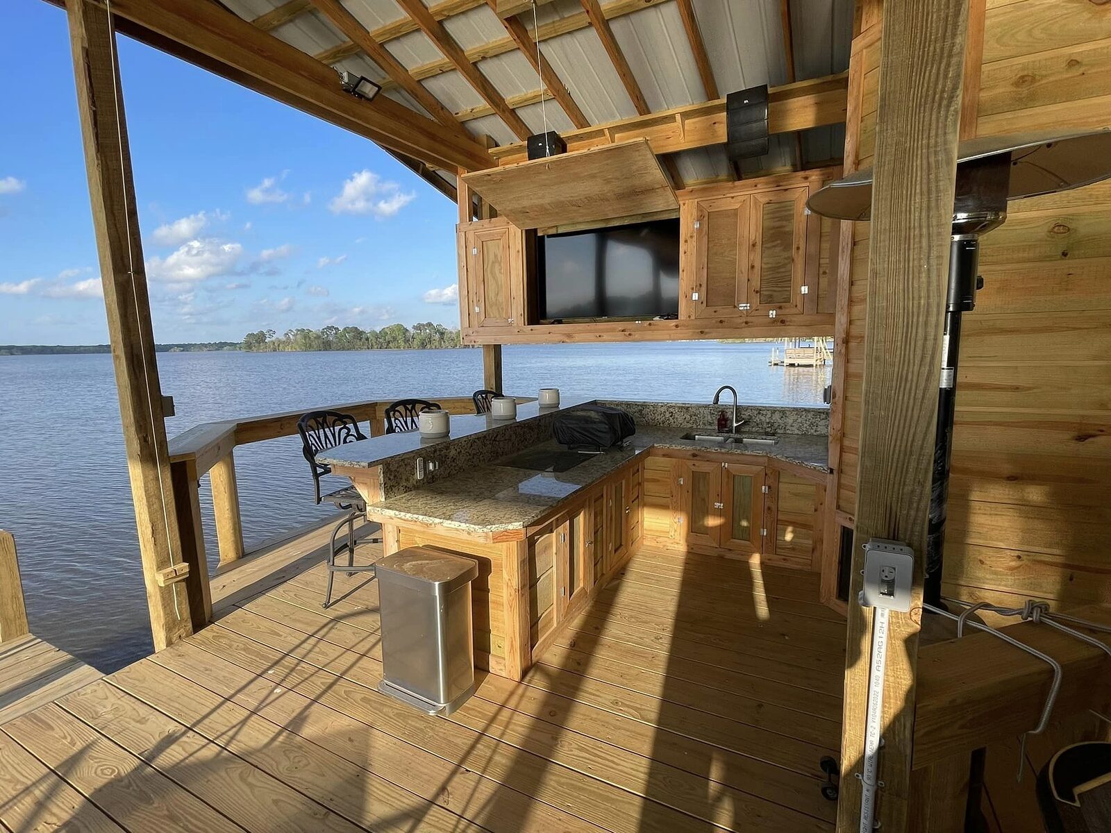 Granite-topped outdoor kitchen and bar seating built into a boathouse overlooking the lake