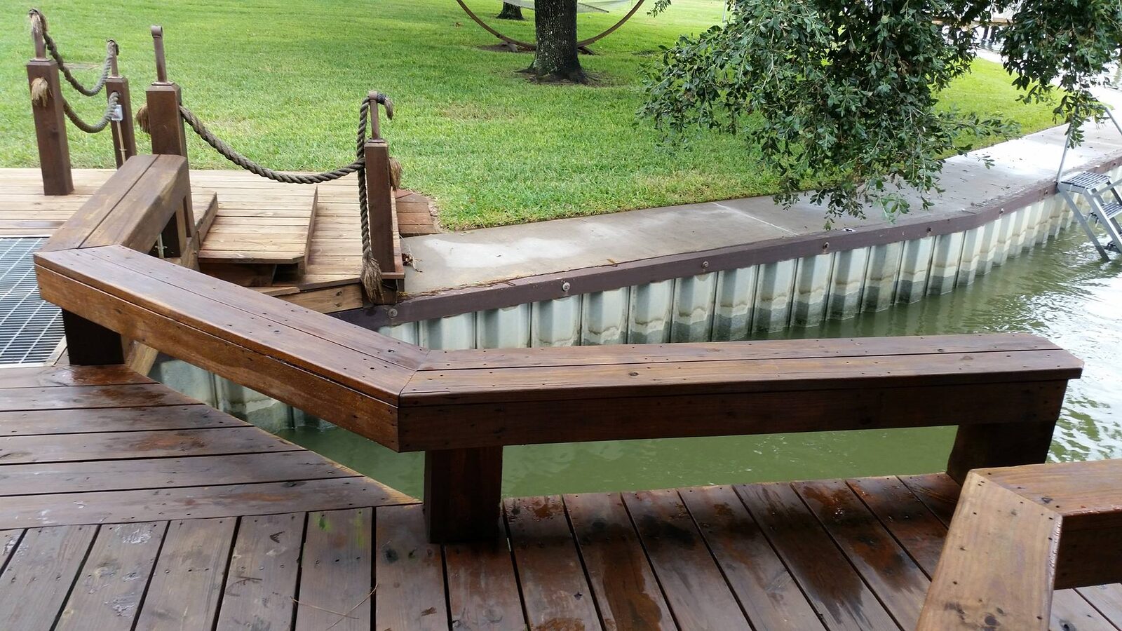 Stained wood dock decking and built-in bench beside a galvanized steel bulkhead, built by Shoretech on Lake Livingston