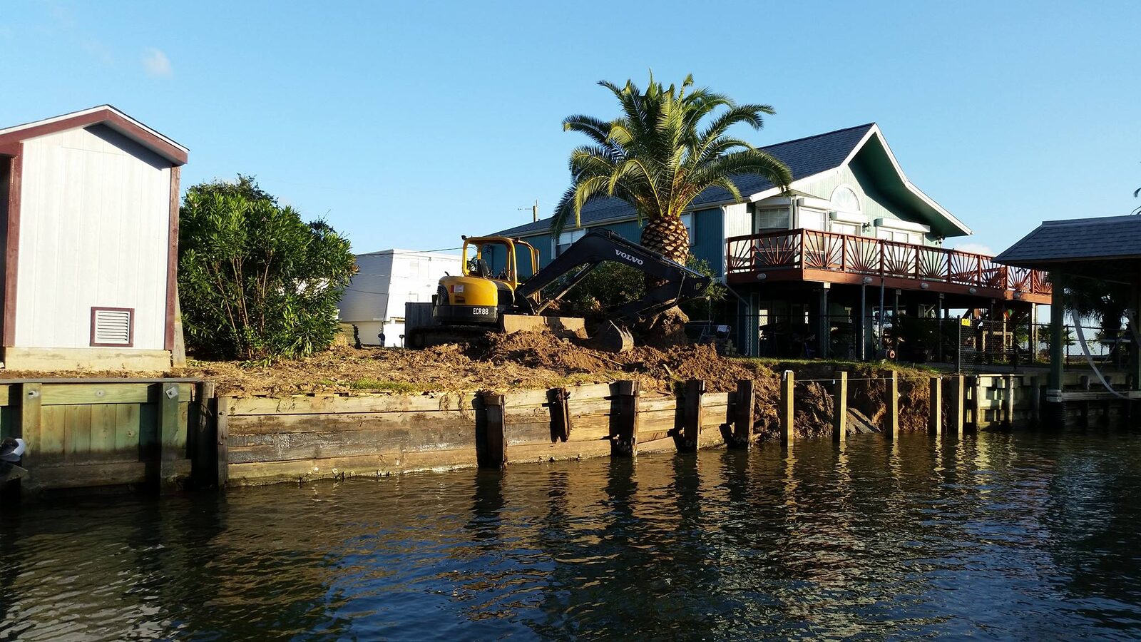 New timber bulkhead along a waterfront lot, with a raised lake home and deck behind it